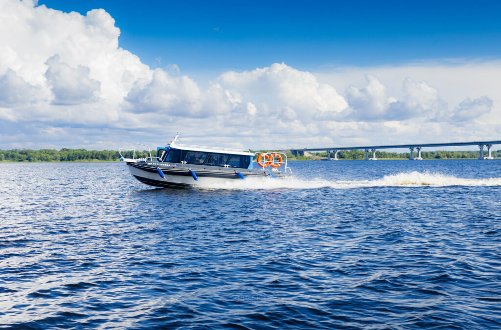 Речной катер на глади воды под облачным небом.