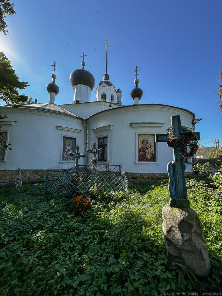 Церковь с куполами и крестами в зелёной местности.