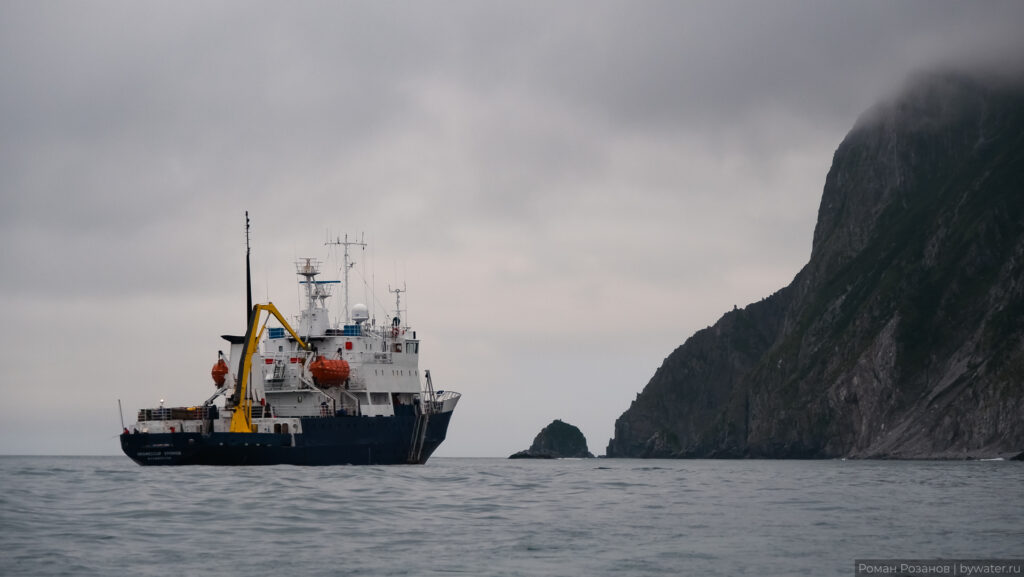 На фоне скал пассажирское судно Профессор Хромов в море.