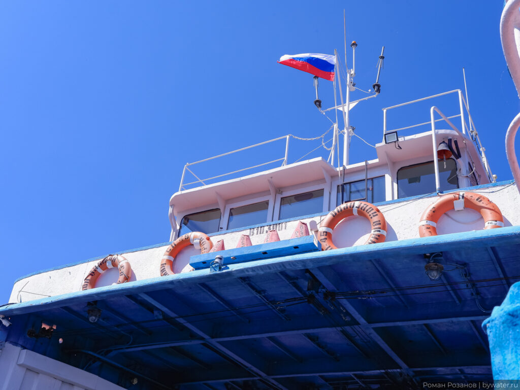 Корпус парома с российским флагом и спасательными кругами.