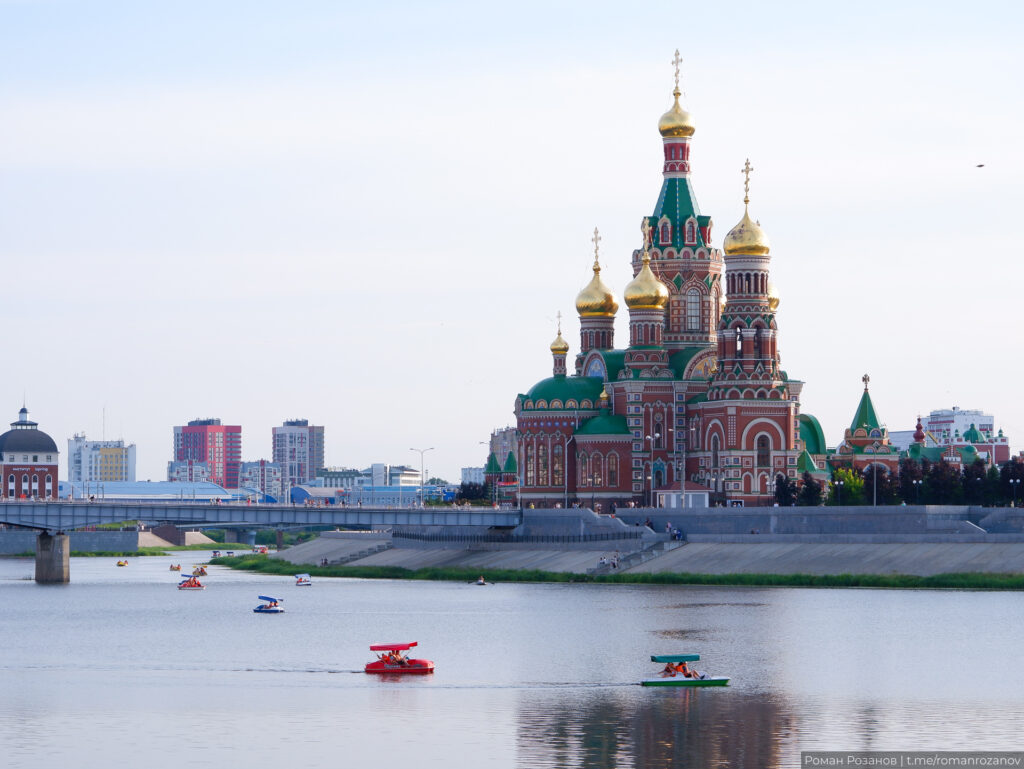 Катера на реке с видом на церковь.