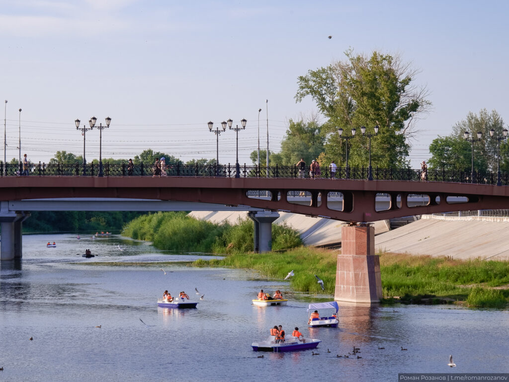 Кораблики на реке под мостом, отдыхающие и зелень.