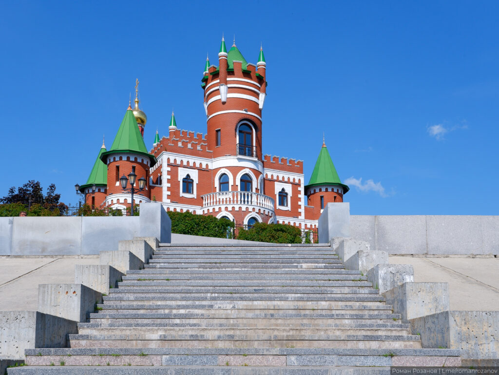 Река, красное здание с зелеными крышами и ступеньками.