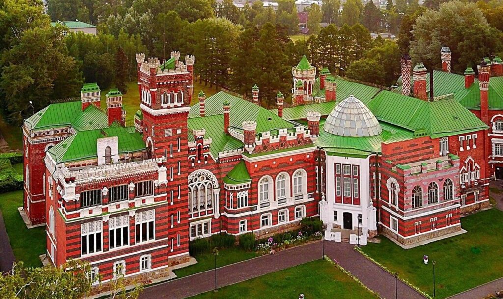 Красивый исторический особняк с зелеными крышами и красным кирпичом.