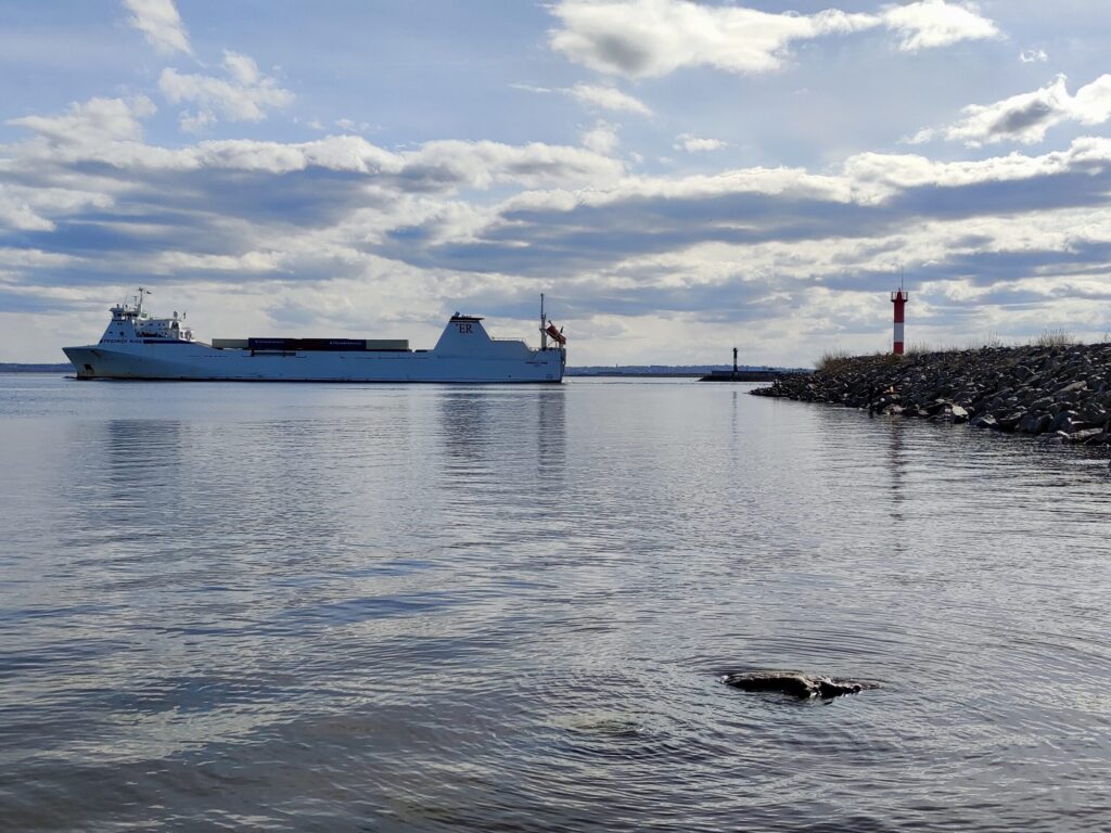 Грузовое судно на подходе к причалу у берега.