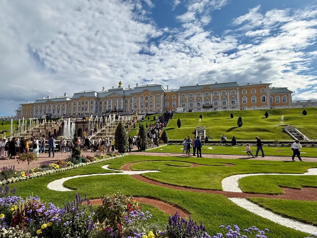 Памятник архитектуры в Петергофе с фонтанами и людьми.