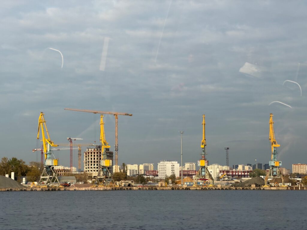 Краны на причале в порту с городскими зданиями.