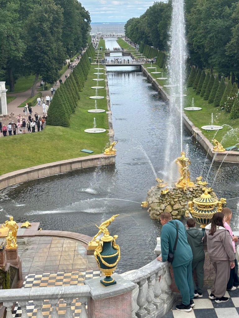 Фонтан в Петергофе с посетителями и садом.